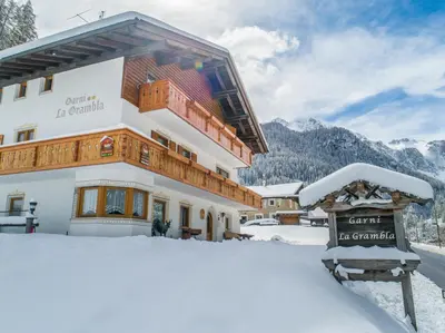a building with a sign in the snow at Garnì La Grambla in Selva di Val Gardena