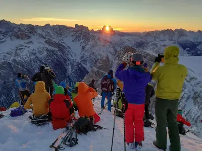 a group of people sitting on top of a mountain watching the sunset at Apartments Frieda in Valdaora