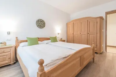 a bedroom with a large bed with white sheets and green pillows at Ferienwohnung Eder in Gais