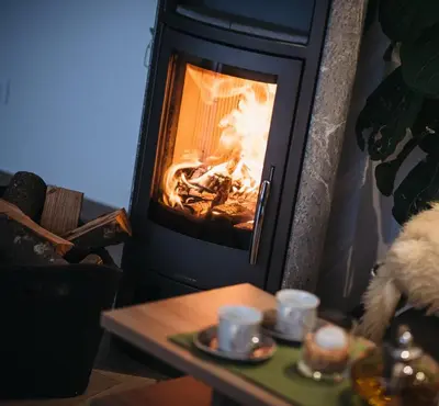 a fire in a fireplace with two cups on a table at Ferienwohnung Eder in Gais