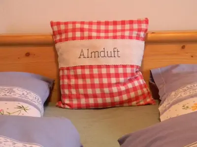 a red and white pillow sitting on a bed at Unterweger Hof in Avelengo