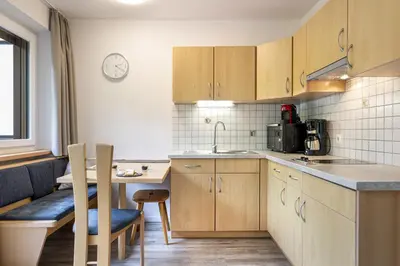 a kitchen with wooden cabinets and a table and chairs at Apartments Woerndle in Siusi