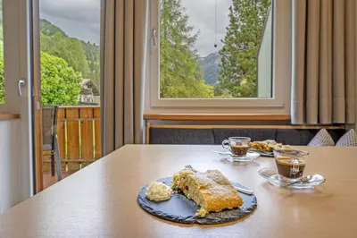 a piece of cake on a table with two drinks at Apartments Woerndle in Siusi