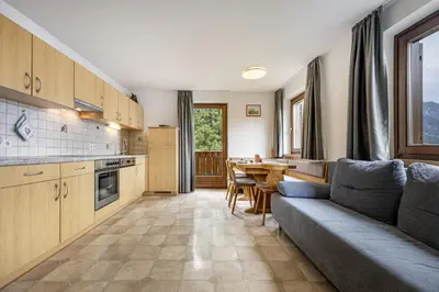 a living room with a couch and a kitchen with a table at Apartments Woerndle in Siusi