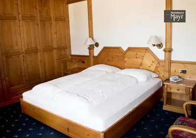 a bedroom with a large bed with a wooden headboard at Residence MAYR in Castelrotto