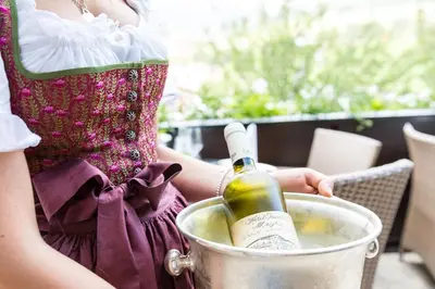 a woman holding a bottle of wine in a bucket at Residence MAYR in Castelrotto