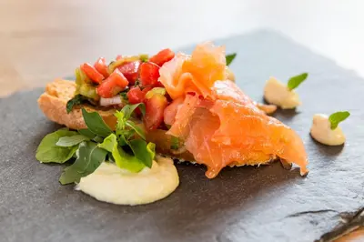 a plate of food with a piece of fish and vegetables at Residence MAYR in Castelrotto