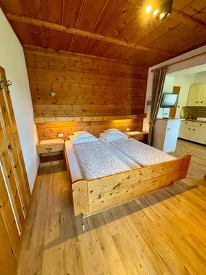a bedroom with a wooden bed in a room at Residence Linde - Ferienwohnungen & Apartments in Castelrotto