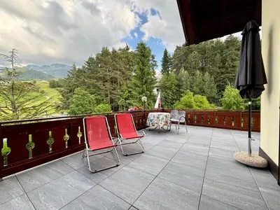 a balcony with chairs and an umbrella and a table at Residence Linde - Ferienwohnungen & Apartments in Castelrotto