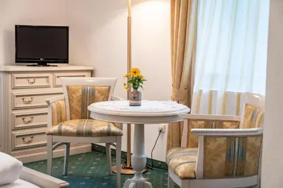 a room with a table and chairs and a tv at Hotel Weisse Lilie - B&B in Mühlbach