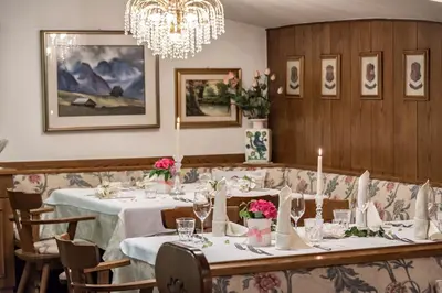 a dining room with tables and chairs and a chandelier at Hotel Weisse Lilie - B&B in Mühlbach