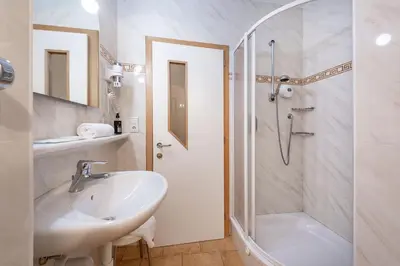 a white bathroom with a shower and a sink at Hotel Weisse Lilie - B&B in Mühlbach