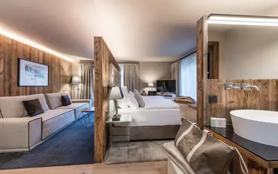 a hotel room with a bed and a sink and a tub at Hotel Montchalet in Ortisei