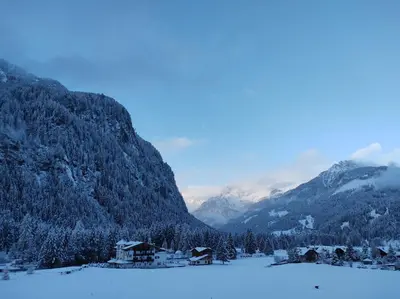 a village in the mountains with snow on the ground at Cianbolpin Guesthouse in Canazei