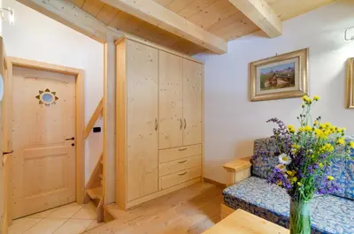 a living room with a couch and a vase of flowers at Cianbolpin Guesthouse in Canazei