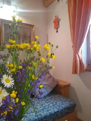 a vase of yellow and purple flowers sitting on a bed at Cianbolpin Guesthouse in Canazei