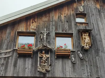 a wooden building with windows and a cross on it at Cianbolpin Guesthouse in Canazei