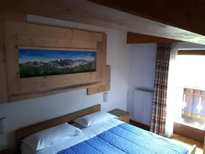 a bedroom with a bed with a painting on the wall at Garni Eden Bed and breakfast in Soraga