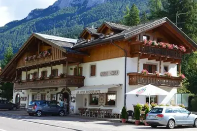 a large building with cars parked in front of it at Garni Eden Bed and breakfast in Soraga