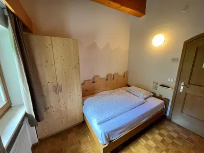 a bedroom with a bed and a wooden cabinet at Garni Eden Bed and breakfast in Soraga
