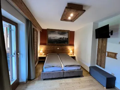 a bedroom with a bed and a tv on the wall at Garni Eden Bed and breakfast in Soraga