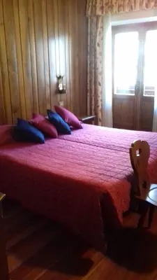 a bedroom with a large bed with red sheets and blue pillows at Dolomiti Sport Hotel in San Vito di Cadore