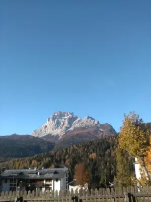 a mountain in the distance with a house and a fence at Dolomiti Sport Hotel in San Vito di Cadore