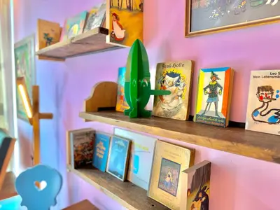 a shelf with books and a toy on a wall at DESIGN APARTMENTS living Kampill in Bolzano
