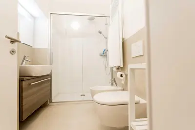 a white bathroom with a toilet and a sink at Stay COOPER l Laubenhaus in Bolzano
