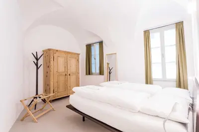 a white room with two beds and a wooden cabinet at Stay COOPER l Laubenhaus in Bolzano