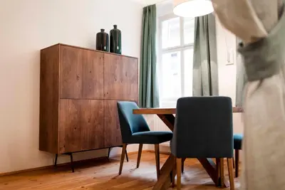 a dining room with a wooden table and blue chairs at Stay COOPER l Laubenhaus in Bolzano