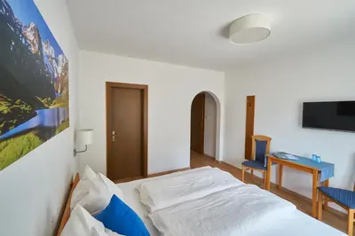 a bedroom with a bed and a desk and a tv at Privatpension Bergkristall in San Martino