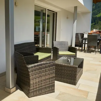 a patio with wicker chairs and a coffee table at Privatpension Bergkristall in San Martino