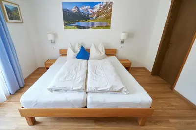 a bedroom with a bed with white sheets and blue pillows at Privatpension Bergkristall in San Martino