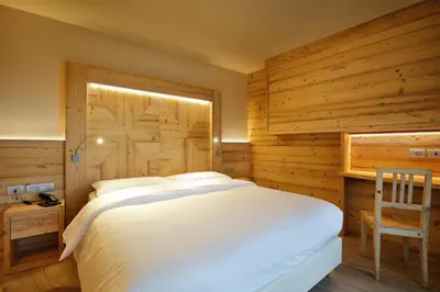 a bedroom with a white bed and a wooden wall at Albergo Garnì Antico Mas del Medico in Cavalese