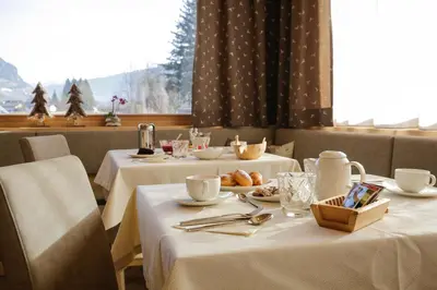a dining room with two tables with white tableclothsurrencyangering at Albergo Garnì Antico Mas del Medico in Cavalese