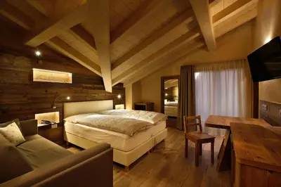 a bedroom with a bed and a table and a couch at Albergo Garnì Antico Mas del Medico in Cavalese