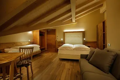 a bedroom with two beds and a couch and a table at Albergo Garnì Antico Mas del Medico in Cavalese