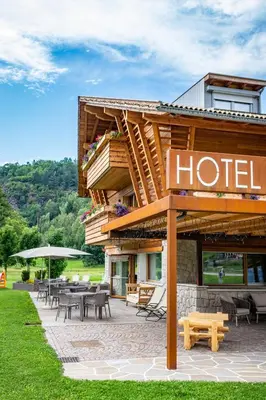 a hotel with tables and chairs in front of it at Albergo Garnì Antico Mas del Medico in Cavalese