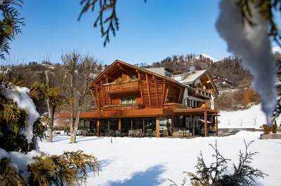 a log home in the snow with snow covered ground at Albergo Garnì Antico Mas del Medico in Cavalese