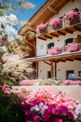 a building with pink flowers in front of it at Albergo Garnì Antico Mas del Medico in Cavalese