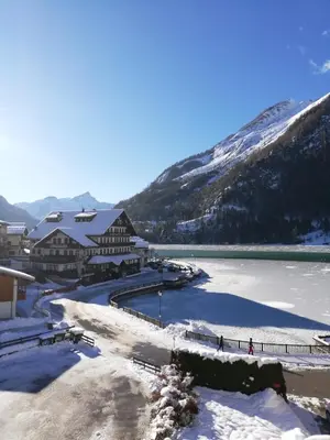 a river in front of a mountain with snow at Una Civetta sul Lago in Alleghe