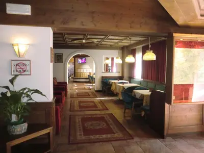 a restaurant with a white piano in a room with tables at Hotel Molino in Falcade