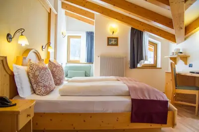 a close up of a bed with a floral blanket at Hotel Genzianella in Ziano di Fiemme