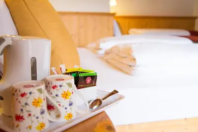 a coffee maker and two cups on a tray next to a bed at Hotel Genzianella in Ziano di Fiemme