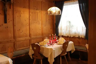a dining room with a table and a chandelier at Hotel Hubertushof in Vipiteno