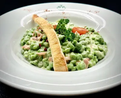 a plate of food with peas and a piece of bread at Hotel Hubertushof in Vipiteno