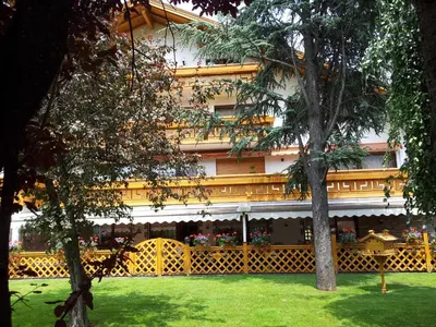 a building with a yellow fence and some trees at Hotel Hubertushof in Vipiteno