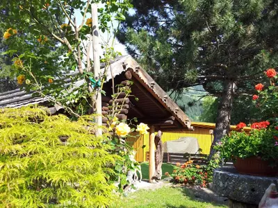 a small yellow house with a roof in a yard at Hotel Hubertushof in Vipiteno