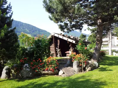 a small log cabin with flowers in a yard at Hotel Hubertushof in Vipiteno